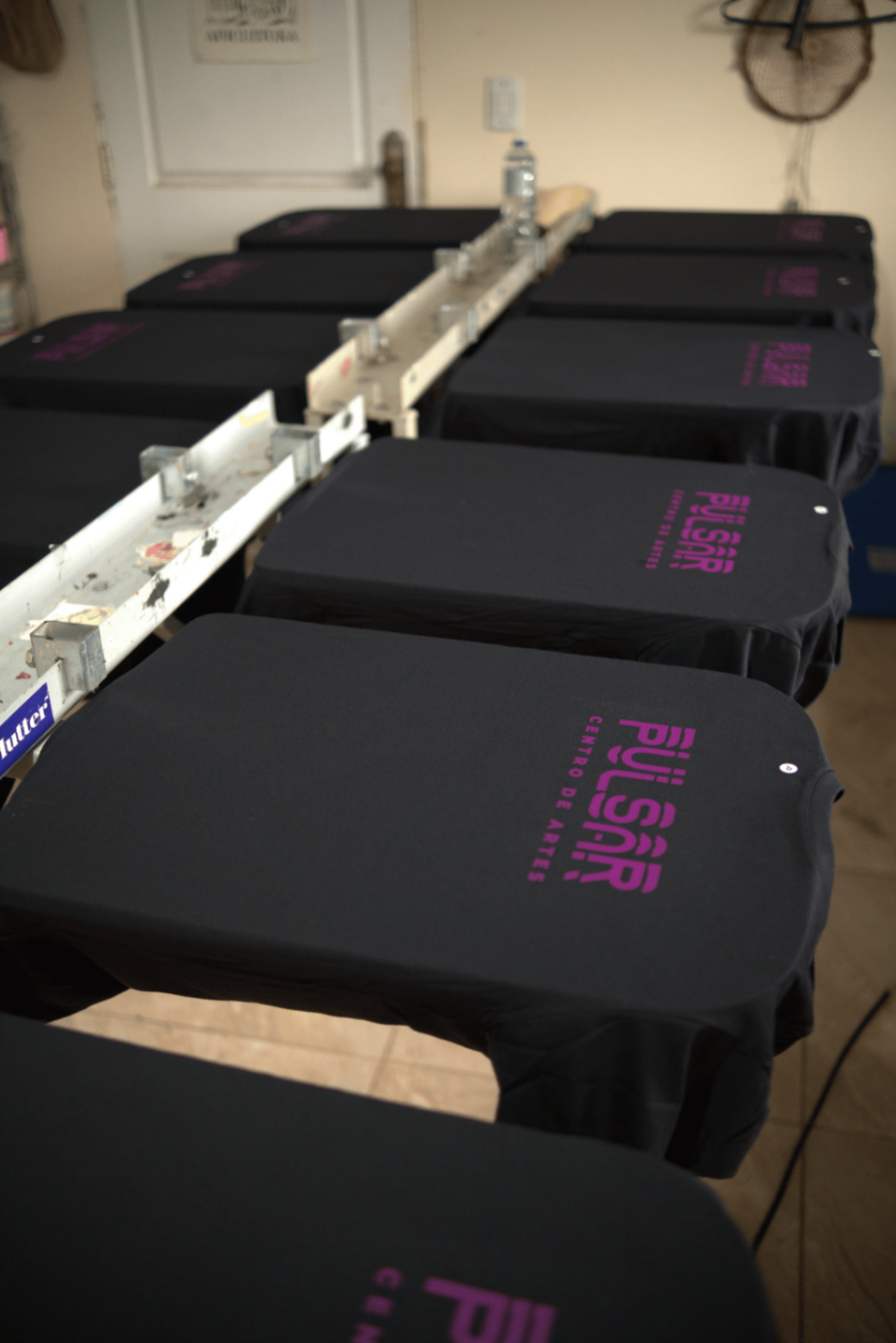 Camisetas pretas alinhadas na esteira de impressão