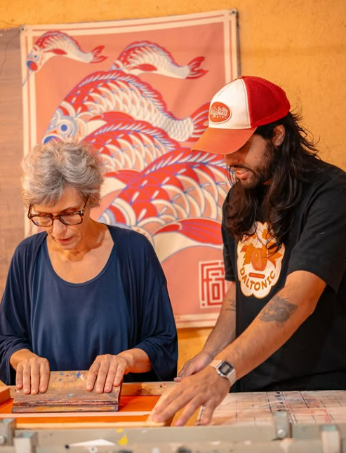 Oficina de serigrafia com duas pessoas estampando juntas