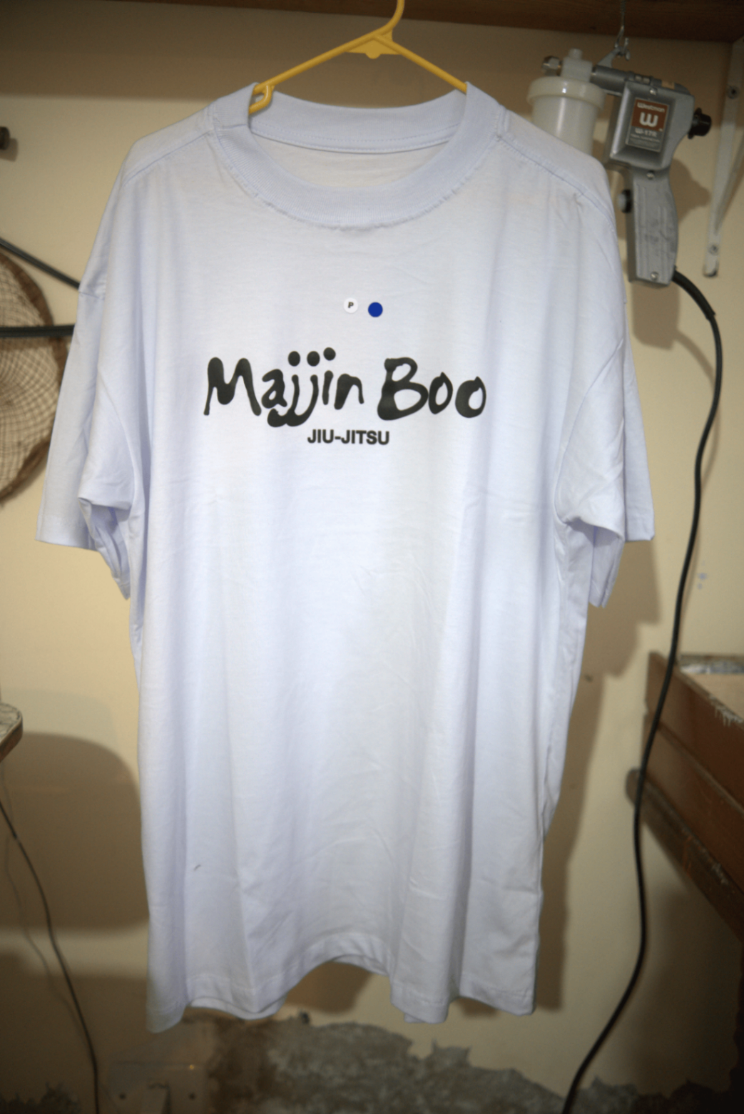 Camiseta branca com estampa Majin Boo Jiu-Jitsu pendurada no ateliê